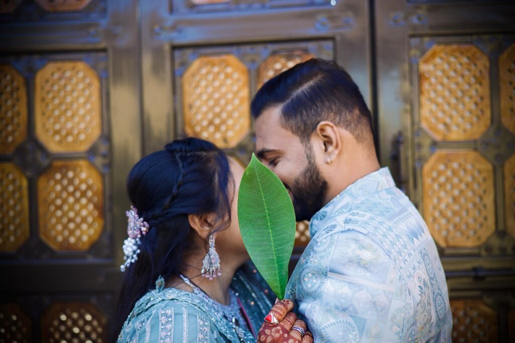 Couple holding a leaf during romantic pre-wedding moment – creative hidden kiss concept