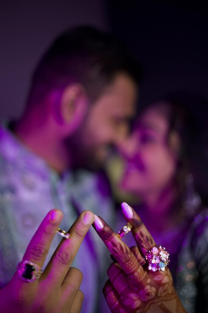 Engagement ring close-up with blurred couple in background – artistic pre-wedding photography